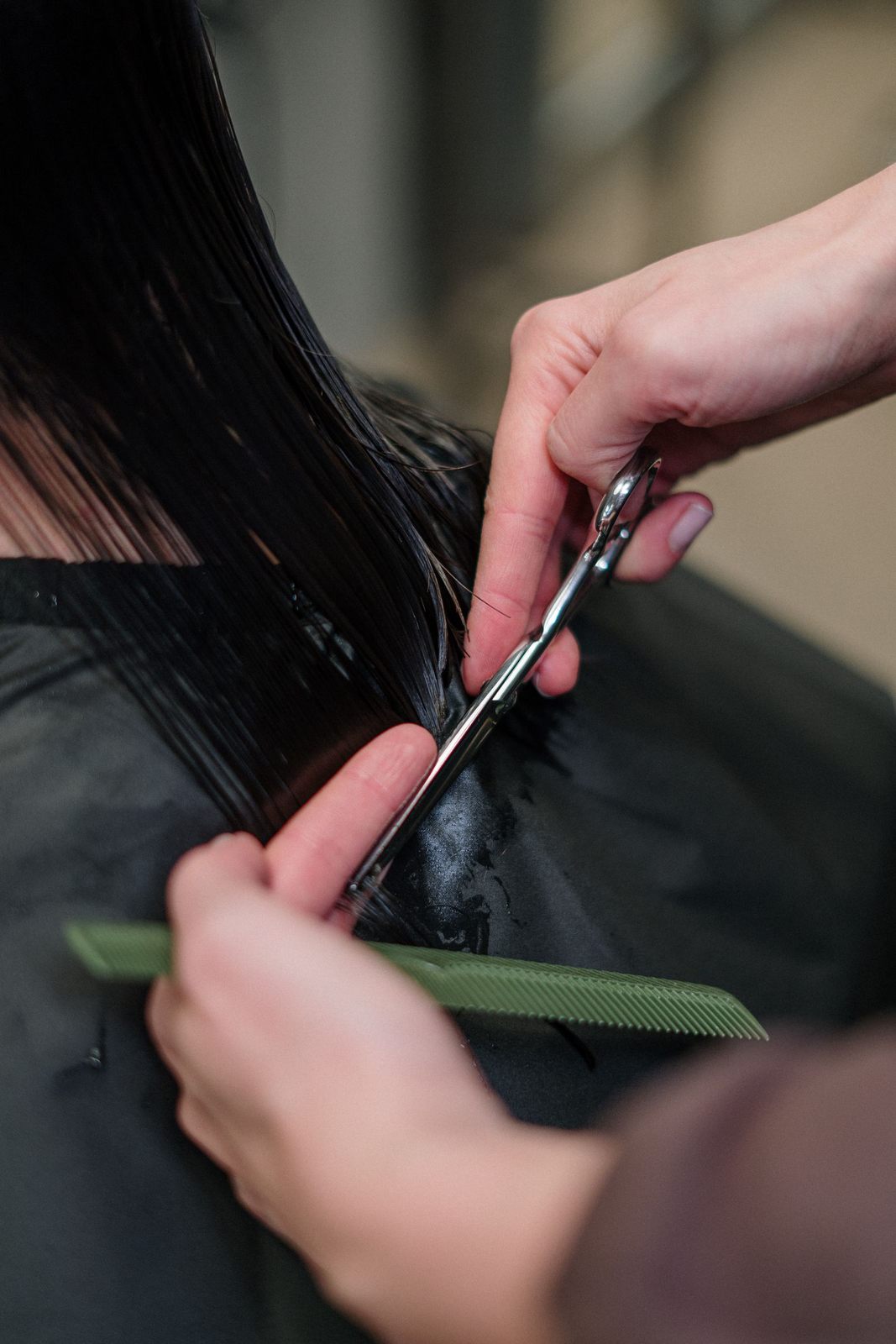 Close-up of a hairdresser cutting black hair in a salon, focusing on precision and style